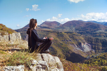 Young Woman Meditating on the Top of the Mountain in Lotus Position. Yoga Outdoor  in the Nature 