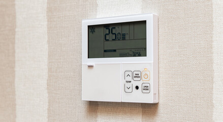 Close-up electronic thermostat on a white wall