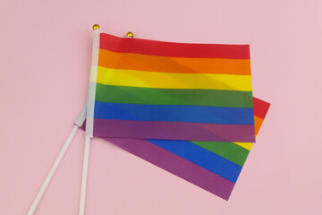 Two LGBT pride rainbow flags on pink background