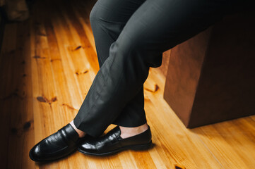 Legs of a man businessman in black shiny shoes on a background of wooden parquet. Business photography.