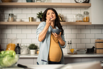 Beautiful pregnant woman having healthy breakfast. Happy woman eating porridge.
