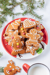 Gingerbread cookies in shape of ginger man placed on red plate. White background. Traditional Christmas dessert decorated. Playful and happy.