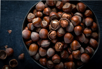 Above view of a wooden bowl with hazelnuts. Hazelnuts in a bowl on a dark background. Close-up. Top view.