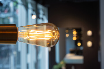 Close up to tungsten lamp light that is hung on the steel stock of ceiling on blur background.