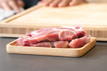 Raw Pork is prepared for Cook, It is on wood plate on black granite kitchen counter tabletop, shot by studio light. Clipping Paths.