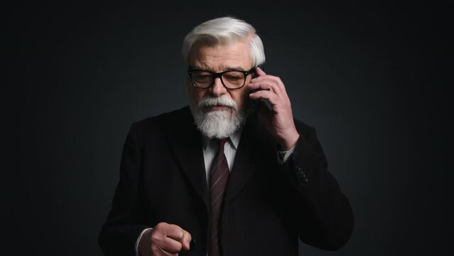 Portrait of gray-haired man holding his gadget while speaking. Close-up shot of retired person gesturing emotionally while talking on the telephone. High quality 4k footage
