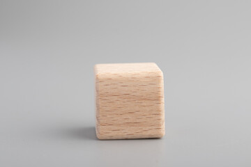 Simple empty wooden dice, one blank cubes made of wood with one central element, gray background. Copy space, logo space in the middle.
