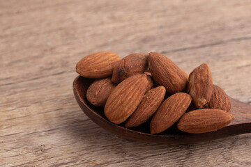 Salted almonds in wooden spoon on wooden background