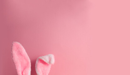 Cute rabbit ears protrude from the border on a pink background copy space