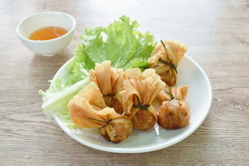 Kratong Thong Thai food made from fried mashed pork stuffed in dumpling flour with lettuce on plate dipping sweet sauce