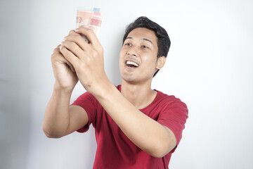 Cheerful man in plaid shirt holding rupiah bills over white background