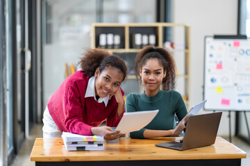 Fototapeta premium A young African-American businesswoman stands for a couple's photo. Join the way of doing business online with documents and a laptop to save data.