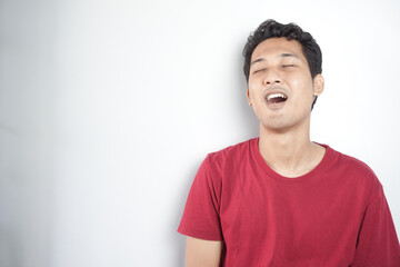 A tired man wearing a red top is yawning