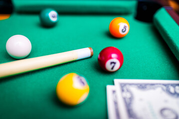 Gambling ardor game.Money and multicolored billiard balls with numbers.Dollar paper banknotes on the game table.Selective focus.