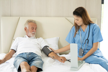 Fototapeta premium Man being cared for by a private Asian nurse at home suffering from Alzheimer's disease to closely care for elderly patients with copy space on left