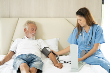 Obraz premium Man being cared for by a private Asian nurse at home suffering from Alzheimer's disease to closely care for elderly patients with copy space on left