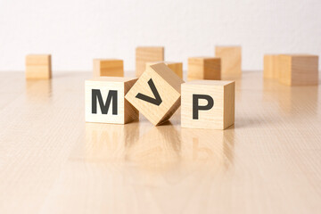 MVP - an abbreviation of wooden blocks with letters on a gray background. reflection caption on the mirrored surface of the table. selective focus