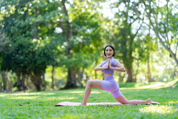 Attractive and strong Asian woman with a beautiful body. yoga in graceful posture in the green park Modern concept of relaxation and health care.