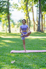 Attractive and strong Asian woman with a beautiful body. yoga in graceful posture in the green park Modern concept of relaxation and health care.