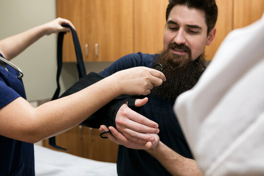 Clinic: Nurse Helps Put Sling On Patient