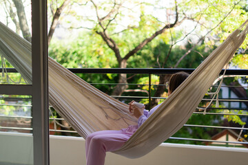 woman in a balcony drinking tea or coffee on a hammock