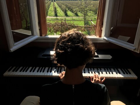 An anonymous woman playing piano with a view