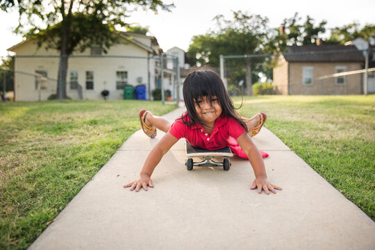 Young girl stopping moving  skateboard down sidewalk
