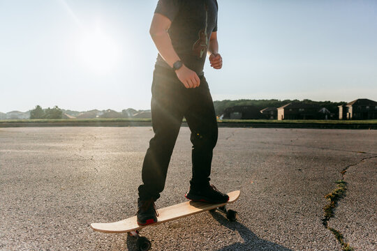 Faceless boy riding longboard on asphalt 