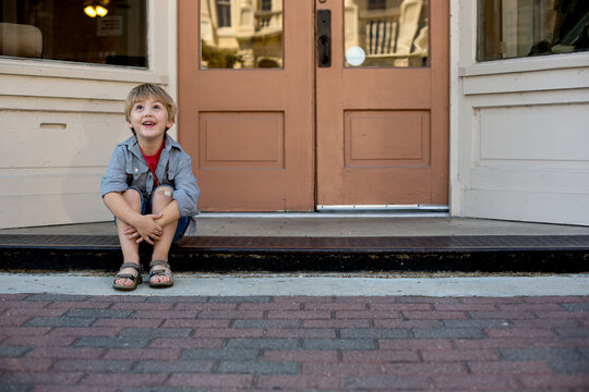 Young boy sitting on store stoop