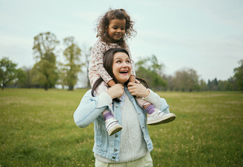 Mother, girl and sitting on shoulders in park for happiness, bonding or care in nature, walk or together outdoor. Woman, child and game on holiday, love or play for adventure at field in Toronto