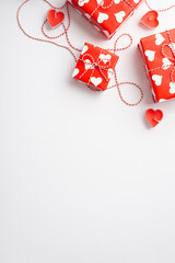 Valentine's Day concept. Top view vertical photo of gift boxes with twine bows and heart shaped candles on isolated white background with copyspace