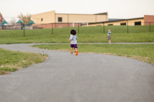 Little girl running to boy on a curved sidewalk