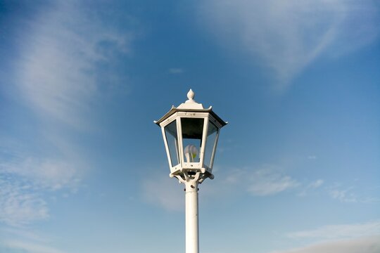 Close up of white old street lamp isolated on blue sky