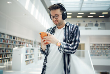 Phone music, headphones and student in library, university, or college research on mental health,...
