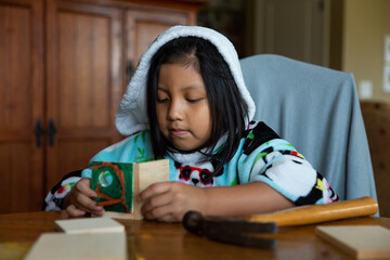 Girl in hooded panda robe building birdhouse 