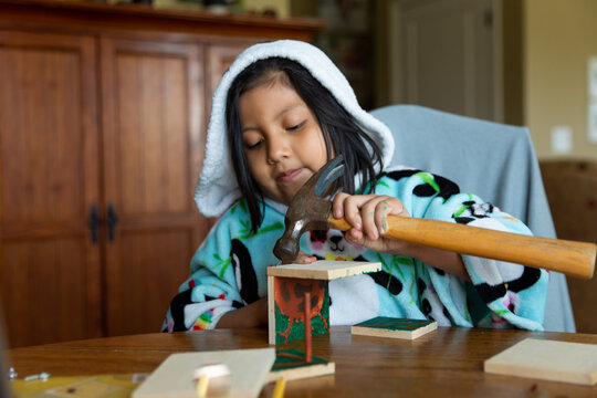Girl in hooded panda robe building birdhouse 
