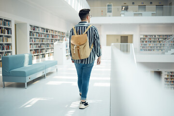 Backpack, library and education with a man student walking in a university bookstore for learning or development. Back, college and research with a male pupil taking a walk in search of a book