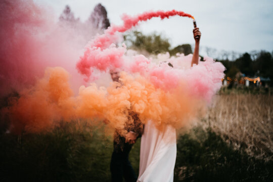 Unrecognizable couple with smoke bombs