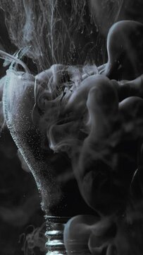 Vertical video. Smoke splash. Ink water. Lamp explosion. Gray fume cloud motion in broken glass light bulb on dark black abstract background.