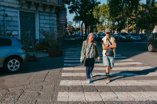 Fototapeta Senior couple tourist crossing street in old italian city in sunlight