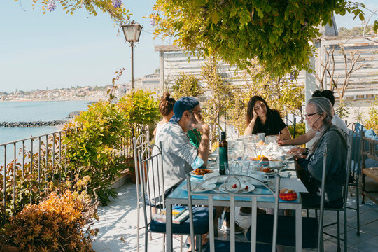 Multigenerational group of people sitting by restaurant terrace table