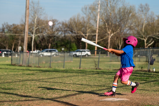 Girl playing baseball wearing colorful uniform 2