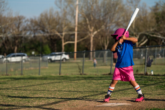 Girl playing baseball wearing colorful uniform