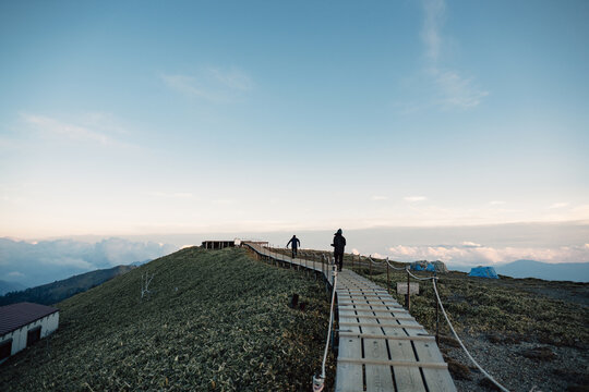 Silhouette of unrecognizable traveler on wooden path