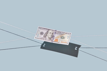 Hundred dollar bill being pulled with threads.