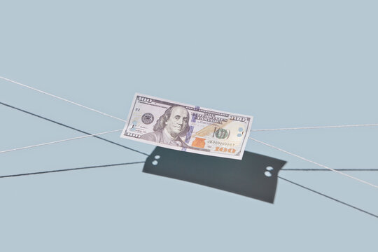 Hundred dollar bill being pulled with threads.