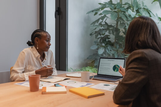 Businesswomen analyzing chart on laptop