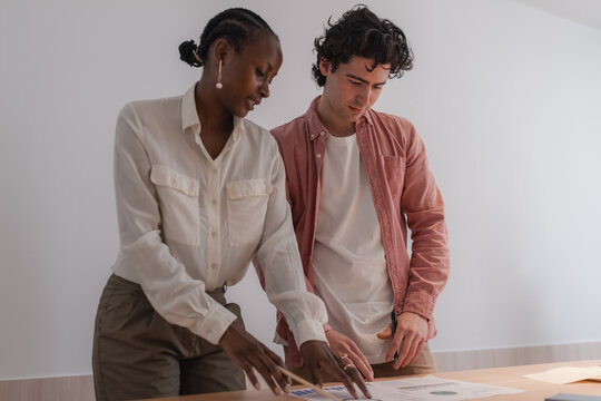 Multiracial colleagues analyzing papers on table