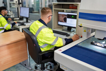 Engineer sitting in robot fabrication room use measuring microscope machine check electronic board