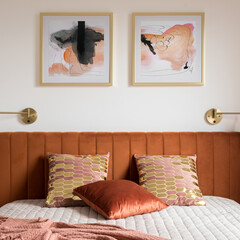 Decorative pillows on bed with velvet headboard, close-up